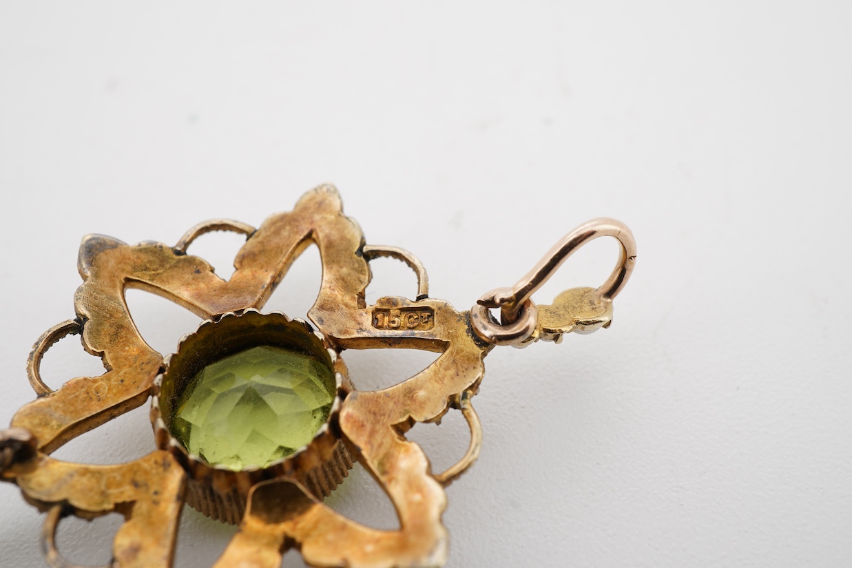 An Edwardian 15ct, peridot and seed pearl cluster pendant, set with circular and pear cut peridot, overall 39mm.
